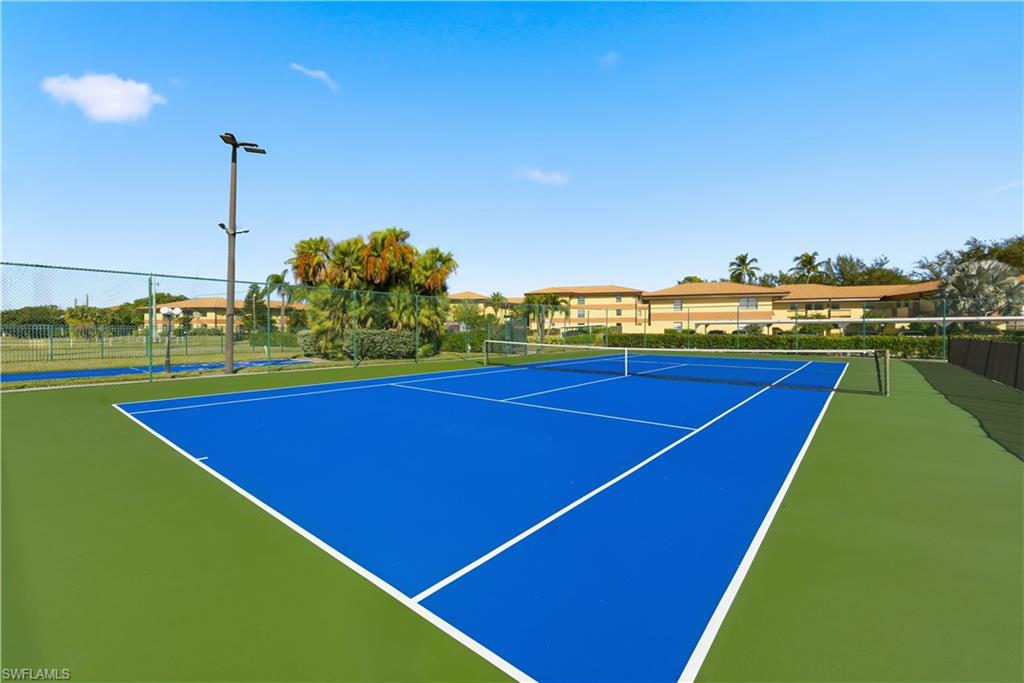 Regulation-size tennis court featuring a blue playing surface with green surrounds