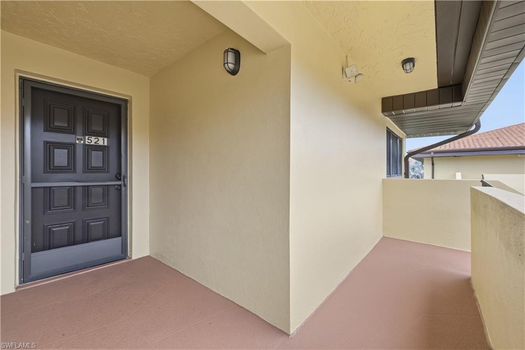 Entryway featuring a paneled door with a security screen, wall-mounted exterior lighting, and a textured ceiling