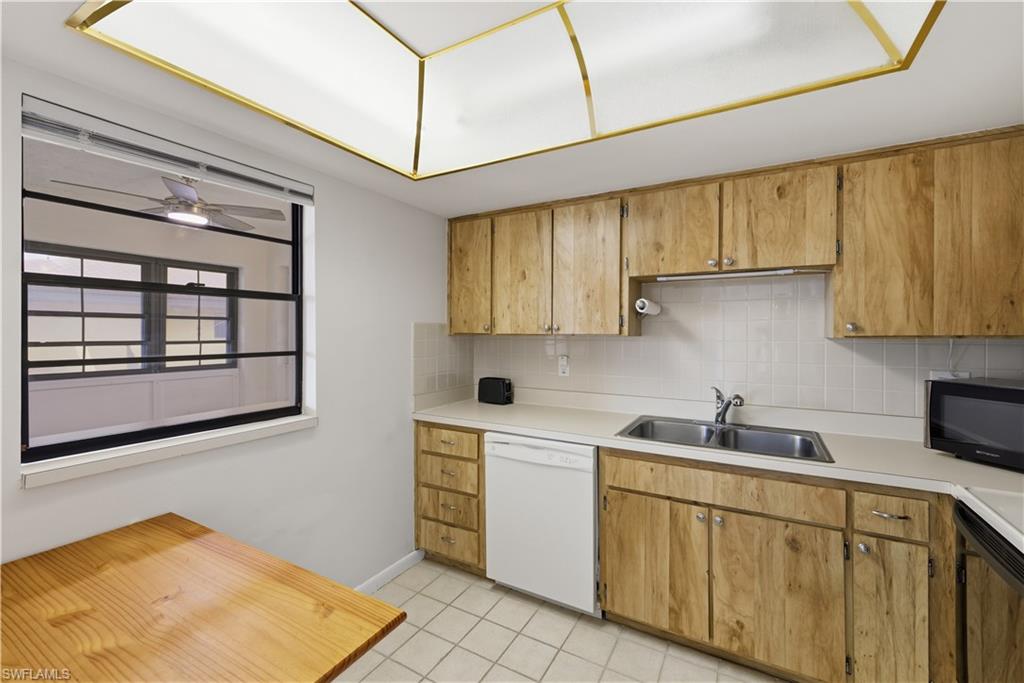 Kitchen featuring wood-finish cabinetry, a dual basin stainless steel sink, and a white tile backsplash