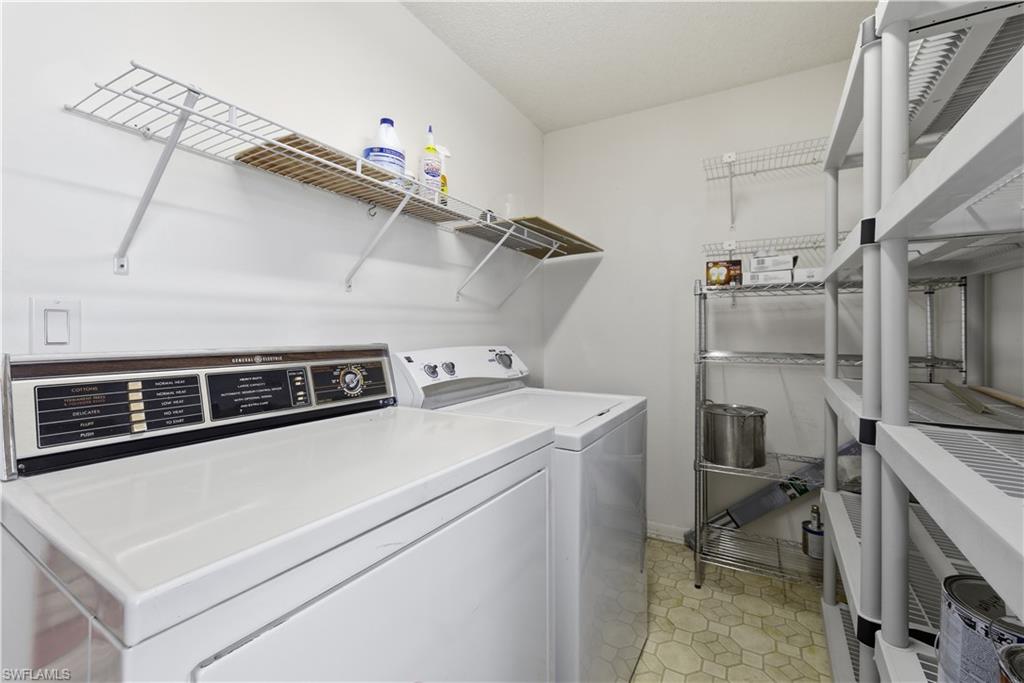 Dedicated laundry space featuring white appliances and honeycomb-patterned flooring