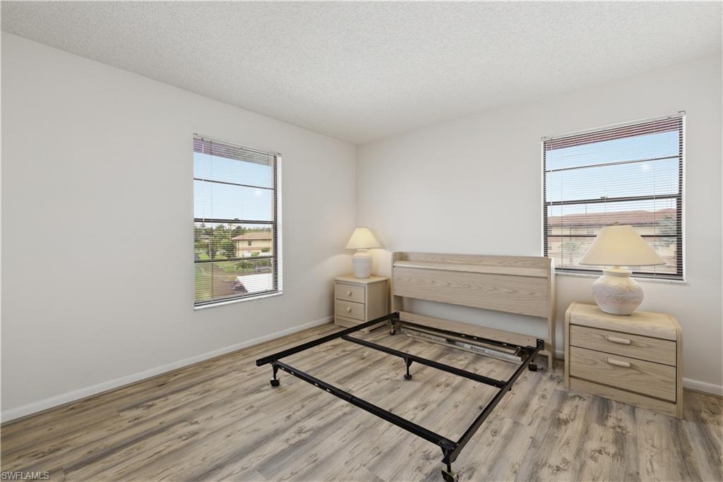 Bright room featuring two windows with horizontal blinds, wood-finish flooring, and white wall finishes