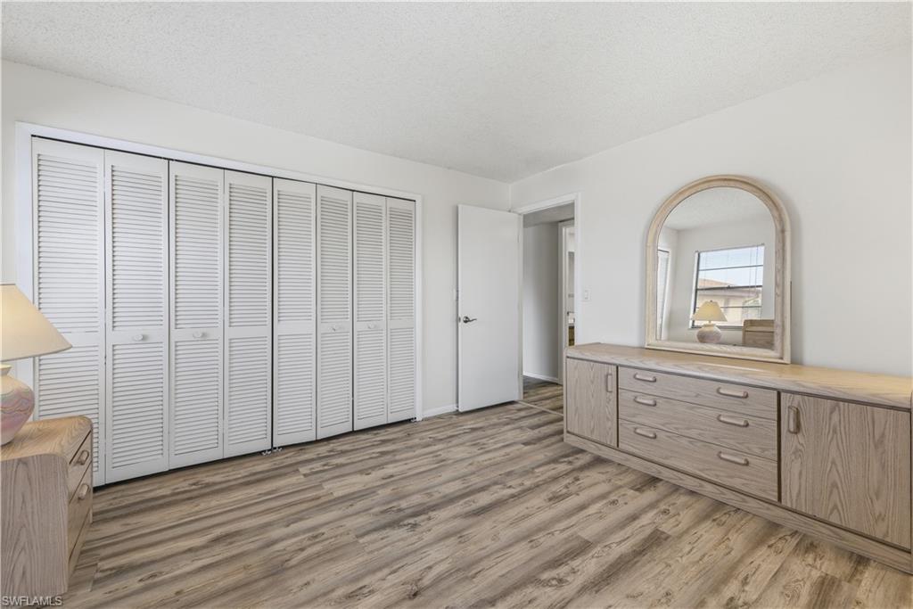 Bedroom featuring wood-finish flooring and a wall of louvered bi-fold closet doors