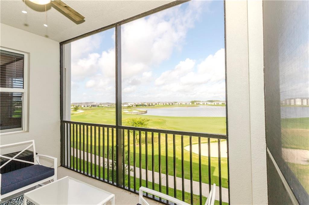 Sunroom with a ceiling fan, view of golf course, and a water view