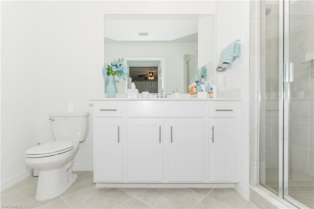 Full bath featuring vanity, toilet, a shower stall, tile patterned flooring, and baseboards
