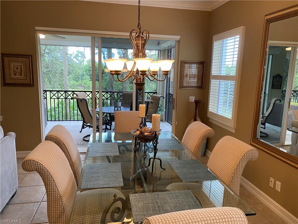 Tiled dining space with suspended lighting and ornamental molding