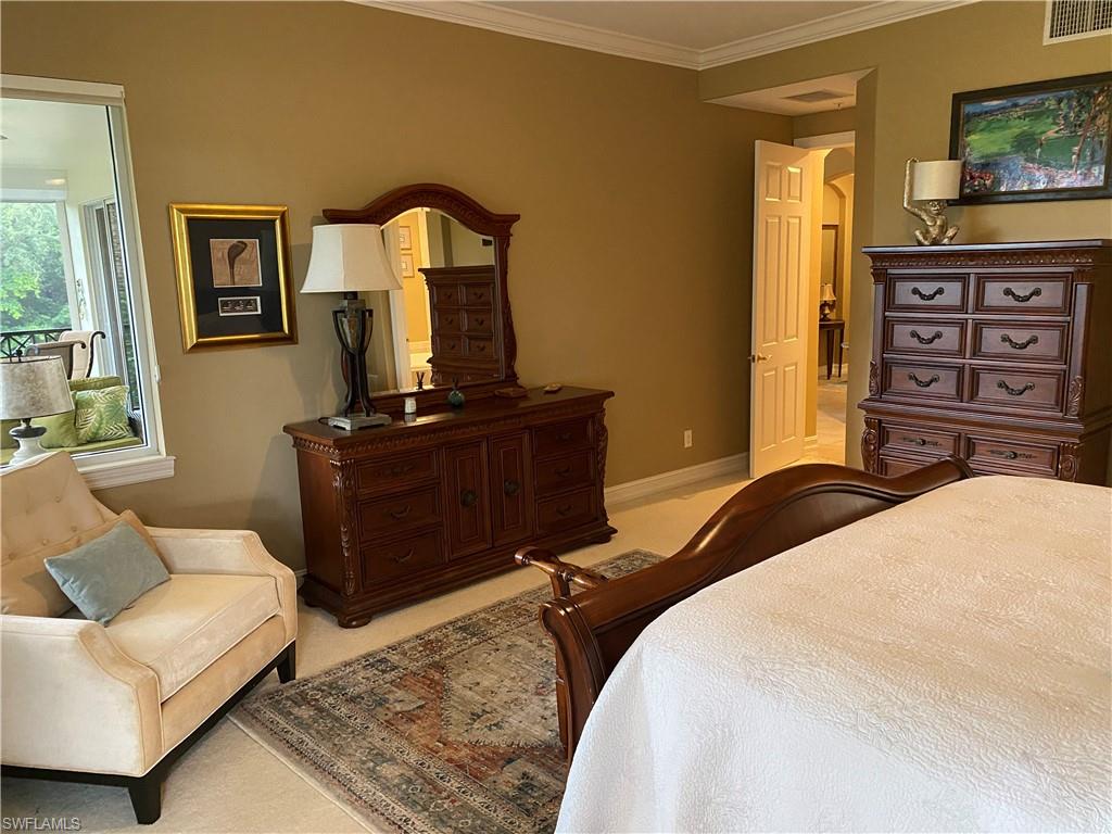 Bedroom with ornamental molding and light colored carpet