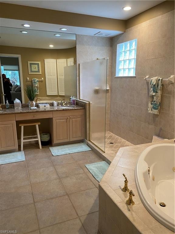 Full bath featuring a jetted tub, vanity, a walk in shower, and recessed lighting