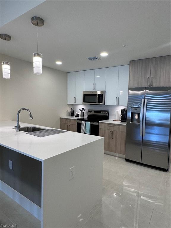 Kitchen with pendant lighting, stainless steel appliances, white cabinets, and sink