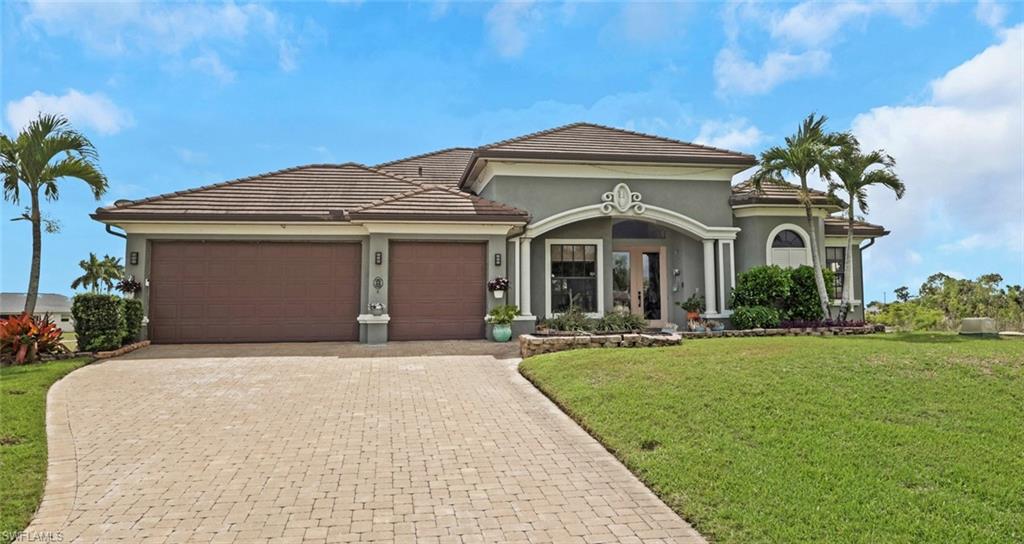 Mediterranean / spanish house with a front lawn, an attached garage, decorative driveway, stucco siding, and a tiled roof