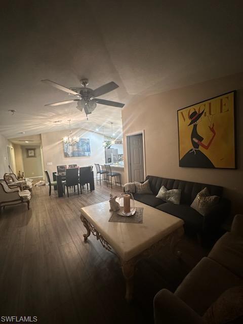 Living room featuring ceiling fan with notable chandelier and hardwood / wood-style flooring