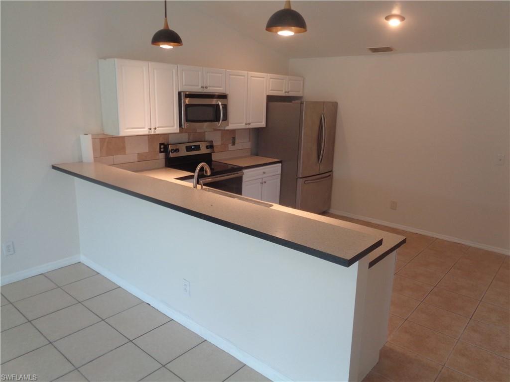 Kitchen with white cabinets, stainless steel appliances, and light tile patterned flooring