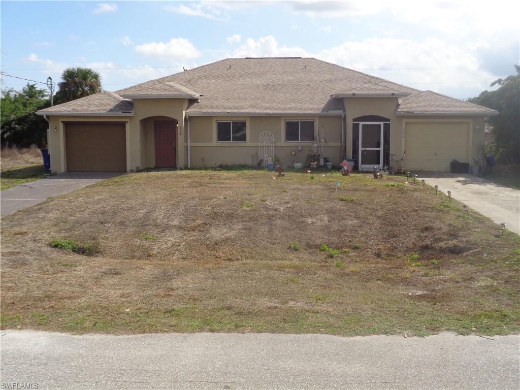 View of front of the duplex with one garage for each unit, concrete driveway, stucco siding, and a shingled roof