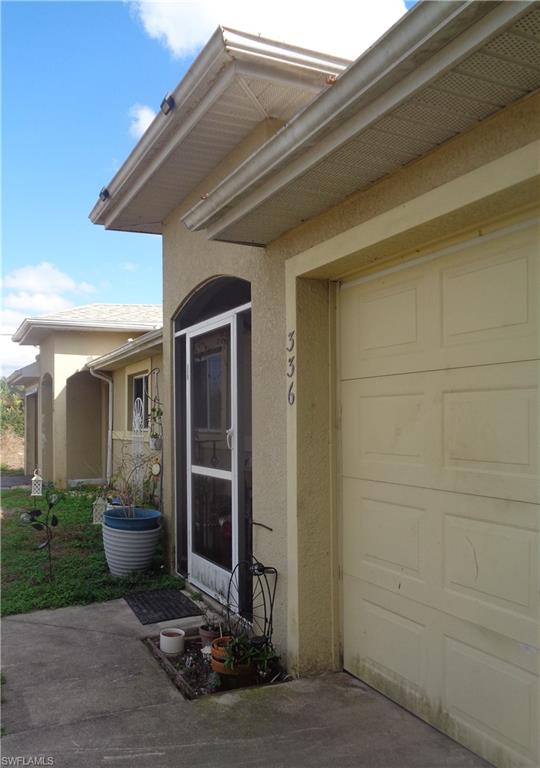 Entrance to property featuring stucco siding and a garage for each unit