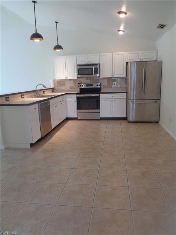 Dining area and kitchen with white cabinets, stainless steel appliances, and light tile patterned flooring