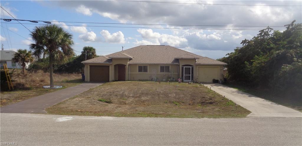 Wide angle view of the front of the duplex with an attached garage for each unit, stucco siding, and driveway