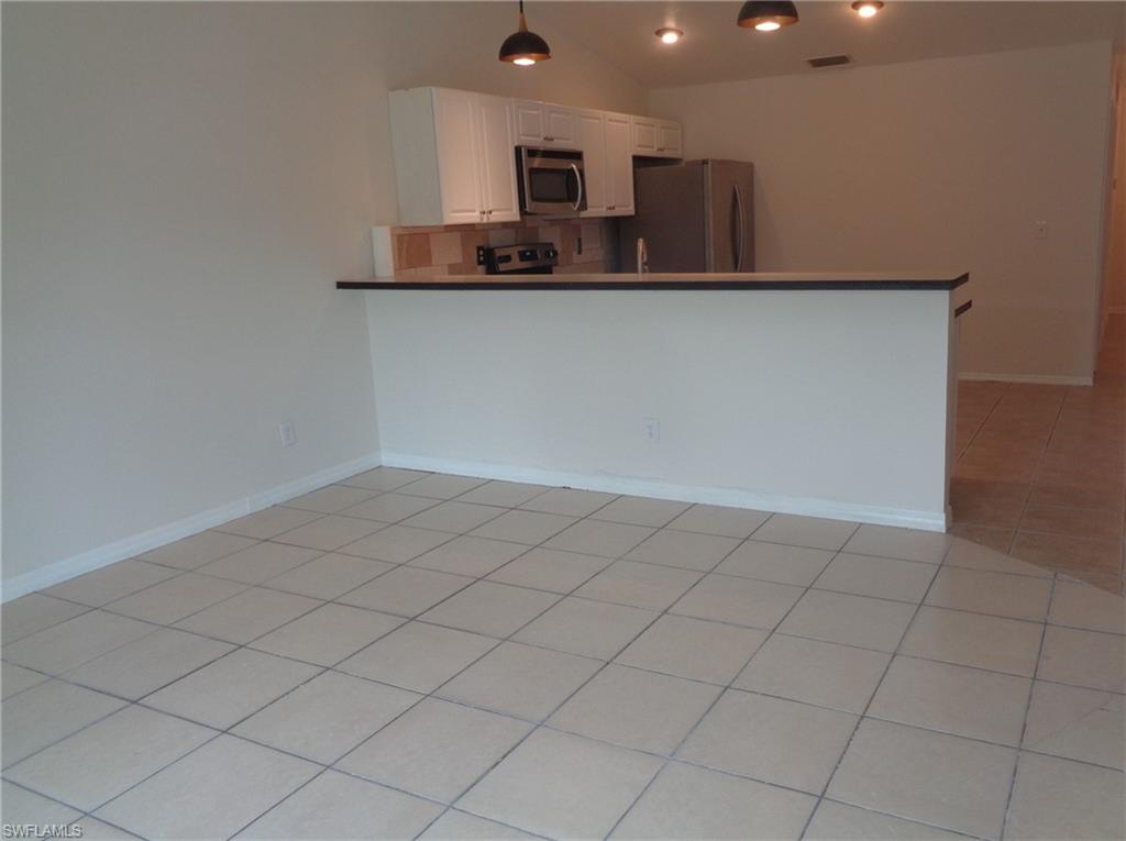 Dining area with light color tile floors. Kitchen can be seen in the back