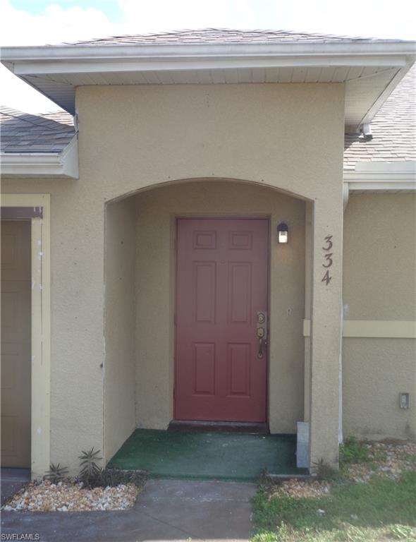 View of exterior entry with stucco siding and roof with shingles