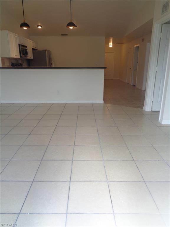 Dining area with light color tile floors. Kitchen can be seen in the back