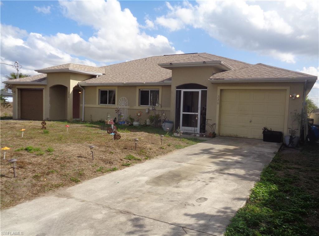 Right view of front of the duplex with a garage for each unit, roof with shingles, stucco siding, a front yard, and concrete driveway