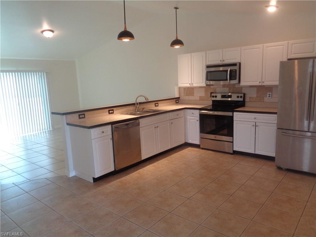Kitchen with white cabinets, stainless steel appliances, and light tile patterned flooring