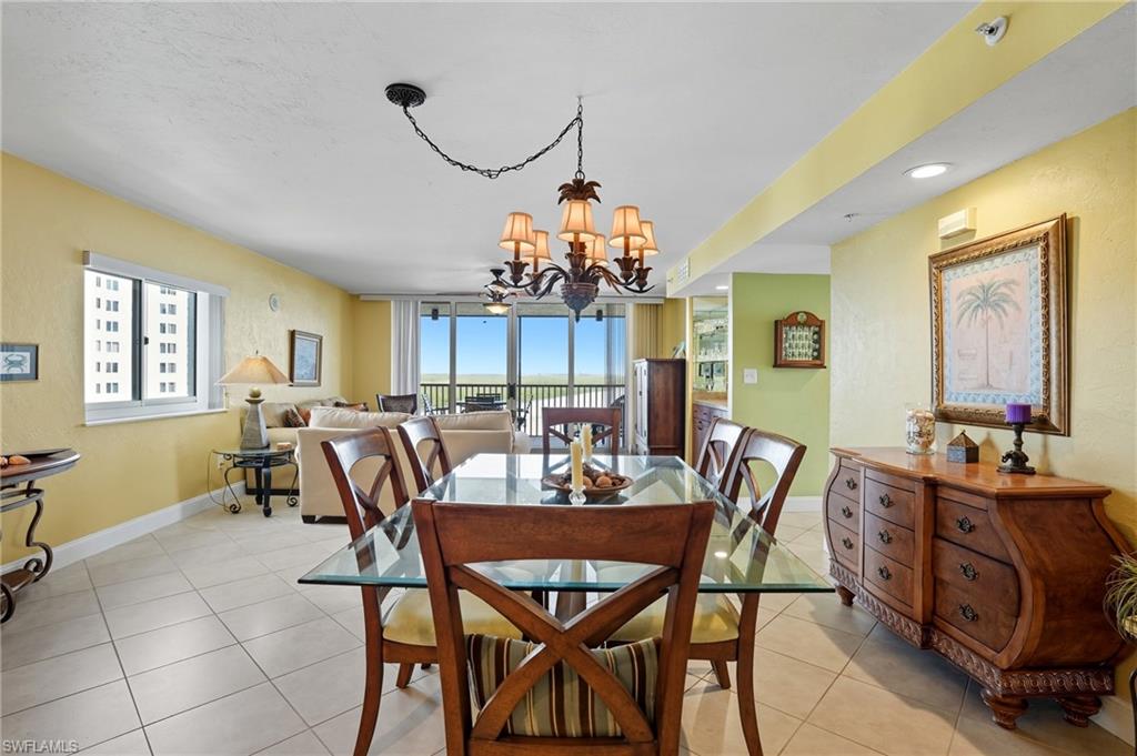 Dining space featuring light tile patterned floors, a chandelier, floor to ceiling windows, and recessed lighting - Virtually Edited Image