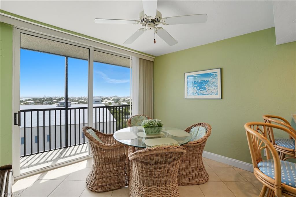 Dining room with light tile patterned floors, a wall of windows, and a ceiling fan - Virtually Edited Image