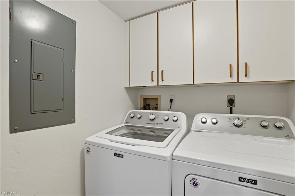 Laundry area featuring electric panel, cabinet space, and washing machine and dryer - Virtually Edited Image