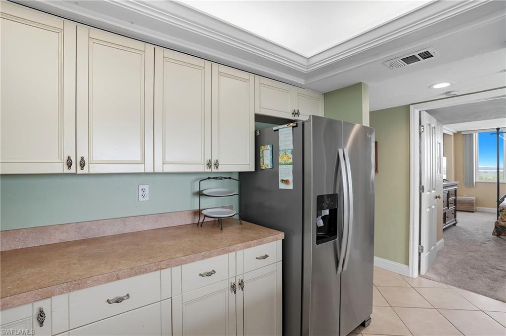 Kitchen featuring stainless steel fridge, light tile patterned floors, light countertops, recessed lighting, and light colored carpet - Virtually Edited Image