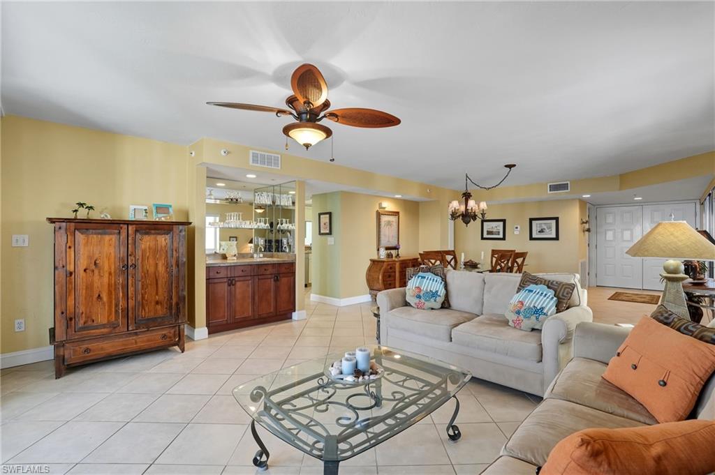 Living area with light tile patterned floors, ceiling fan, and a chandelier - Virtually Edited Image