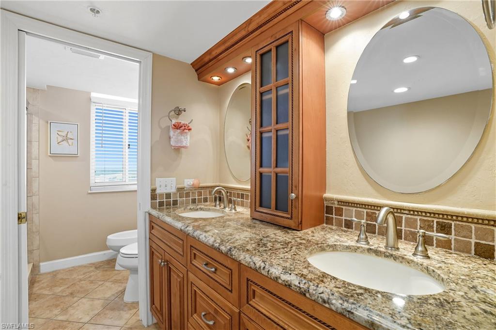 Full bath with tasteful backsplash, double vanity, light tile patterned floors, and recessed lighting - Virtually Edited Image