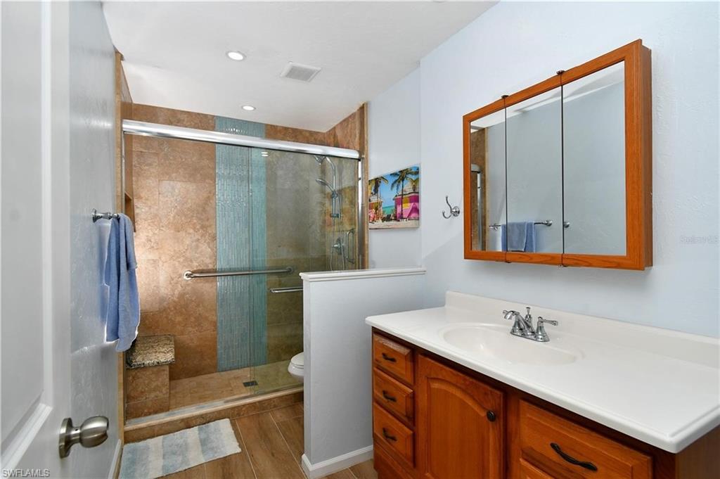 Full guest bath featuring vanity, a stall shower, and light wood finished floors