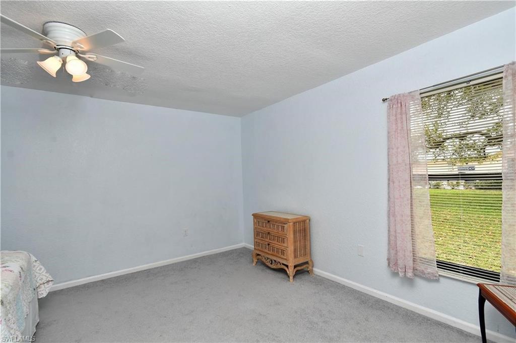 Unfurnished bedroom featuring a ceiling fan, a textured ceiling, and light colored carpet