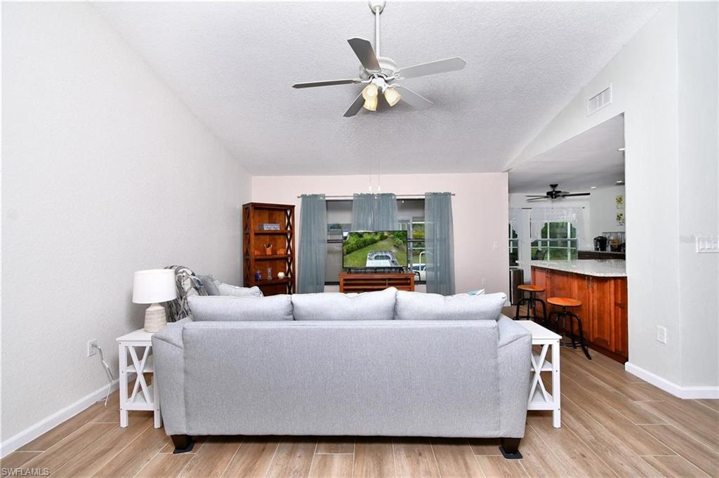 Living room with ceiling fan, light wood-type flooring, and a textured ceiling