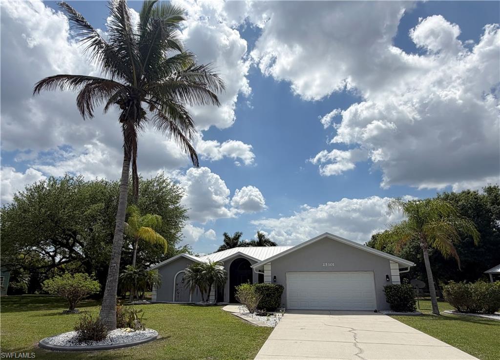Ranch-style house featuring a front yard, an attached garage, stucco siding, and concrete driveway