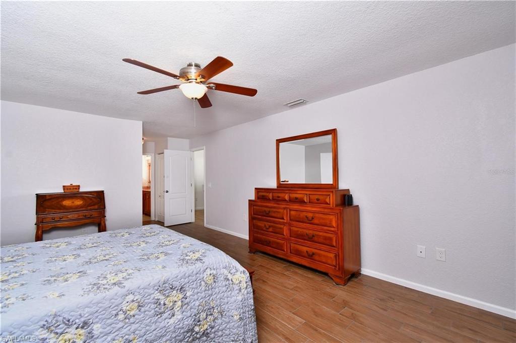Bedroom with dark wood finished floors, a textured ceiling, a ceiling fan, and ensuite bathroom