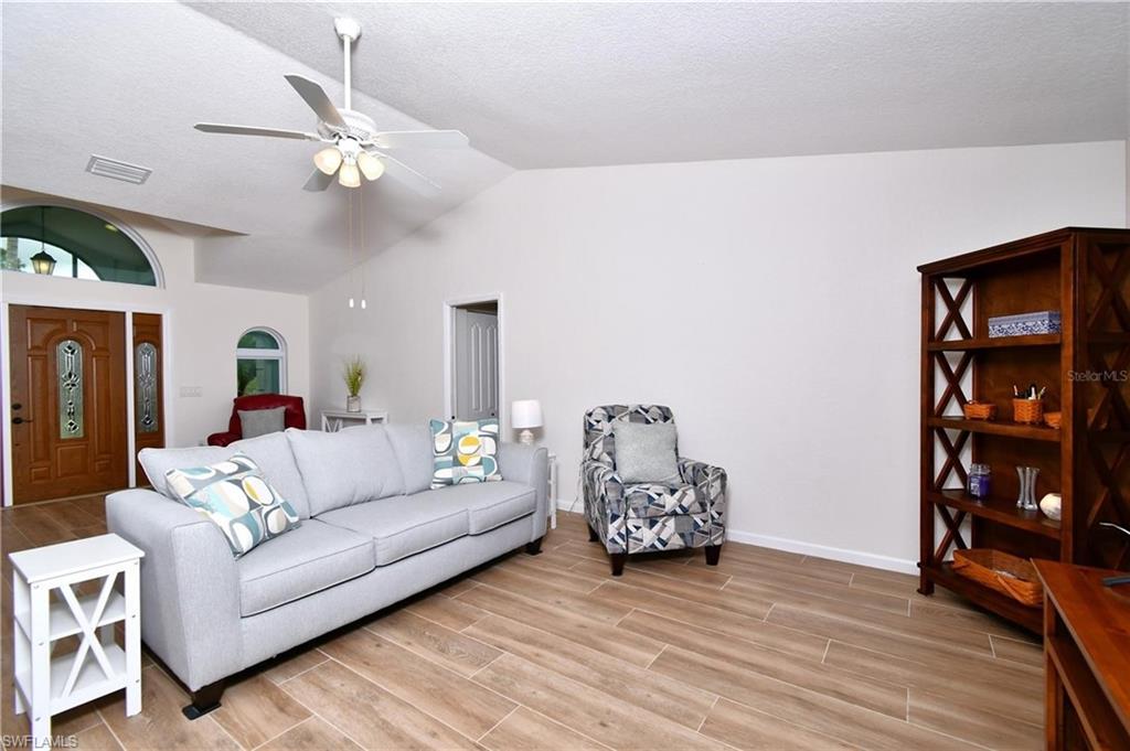 Living room with wood tiled floors, a ceiling fan, and a high textured ceiling