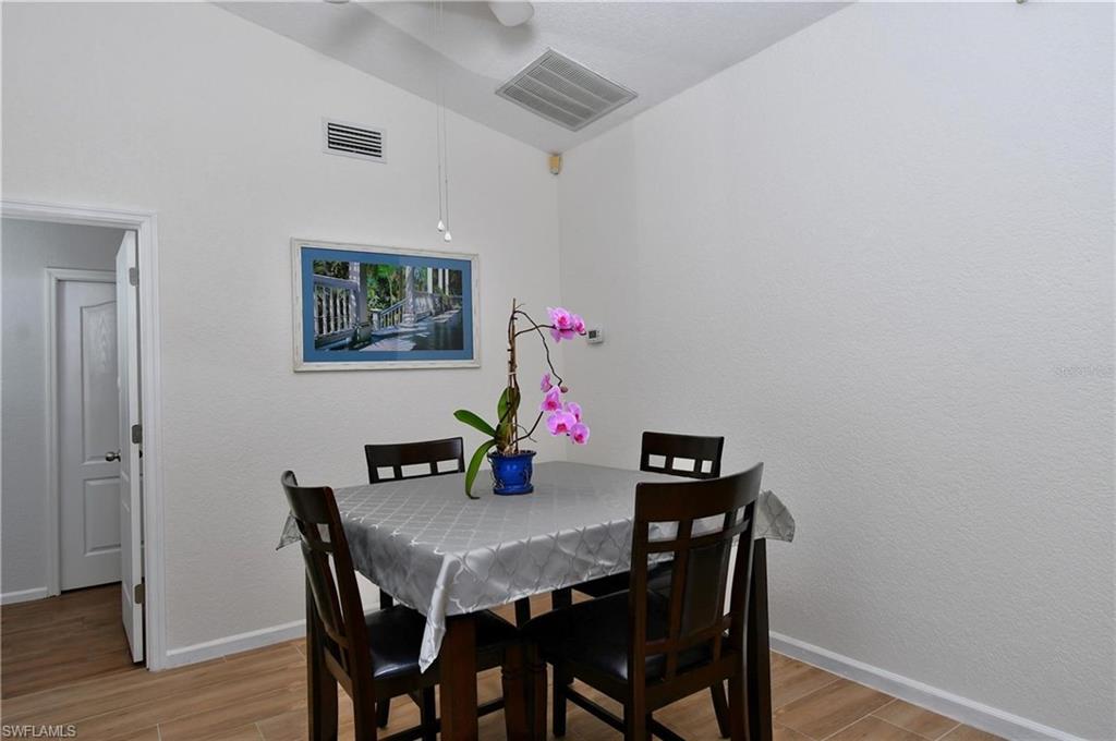 Dining area with lofted ceiling, light wood-style floors, and a textured wall