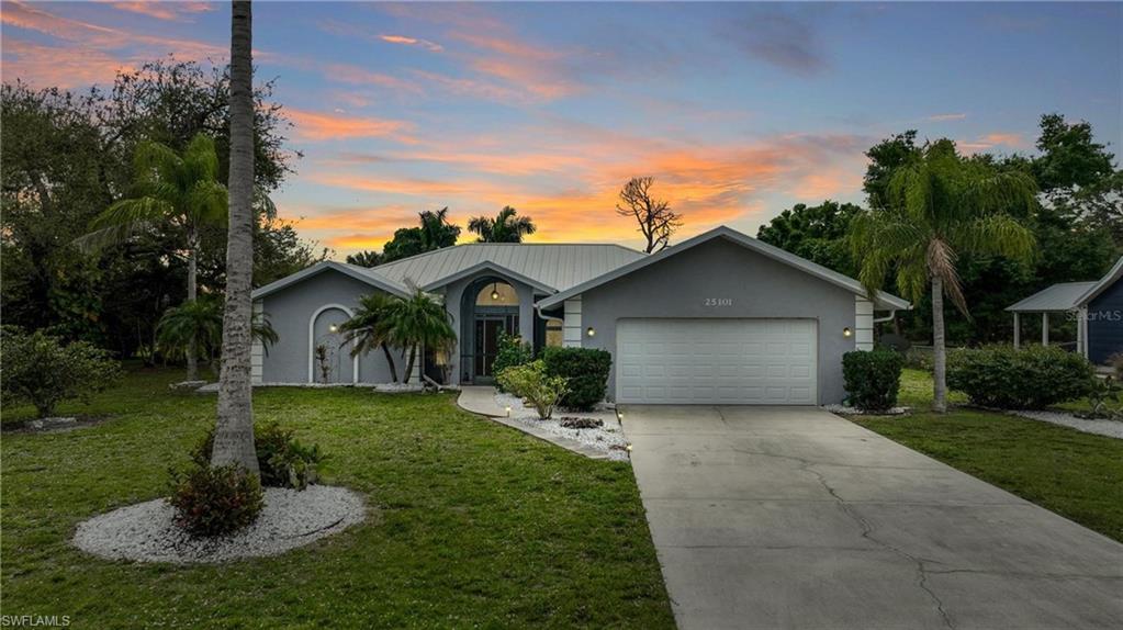Ranch-style house featuring an attached garage, a yard, stucco siding, and concrete driveway