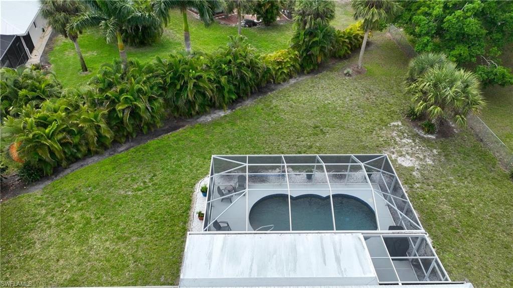 View of grassy yard featuring a lanai and an outdoor pool