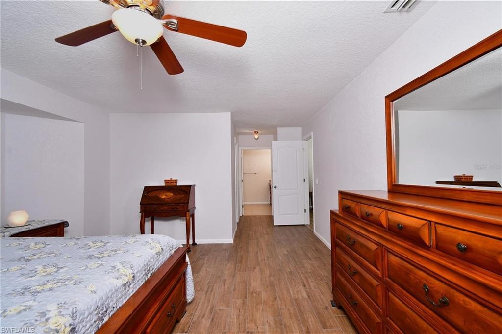 Bedroom with dark wood-style flooring, a textured ceiling, and a ceiling fan