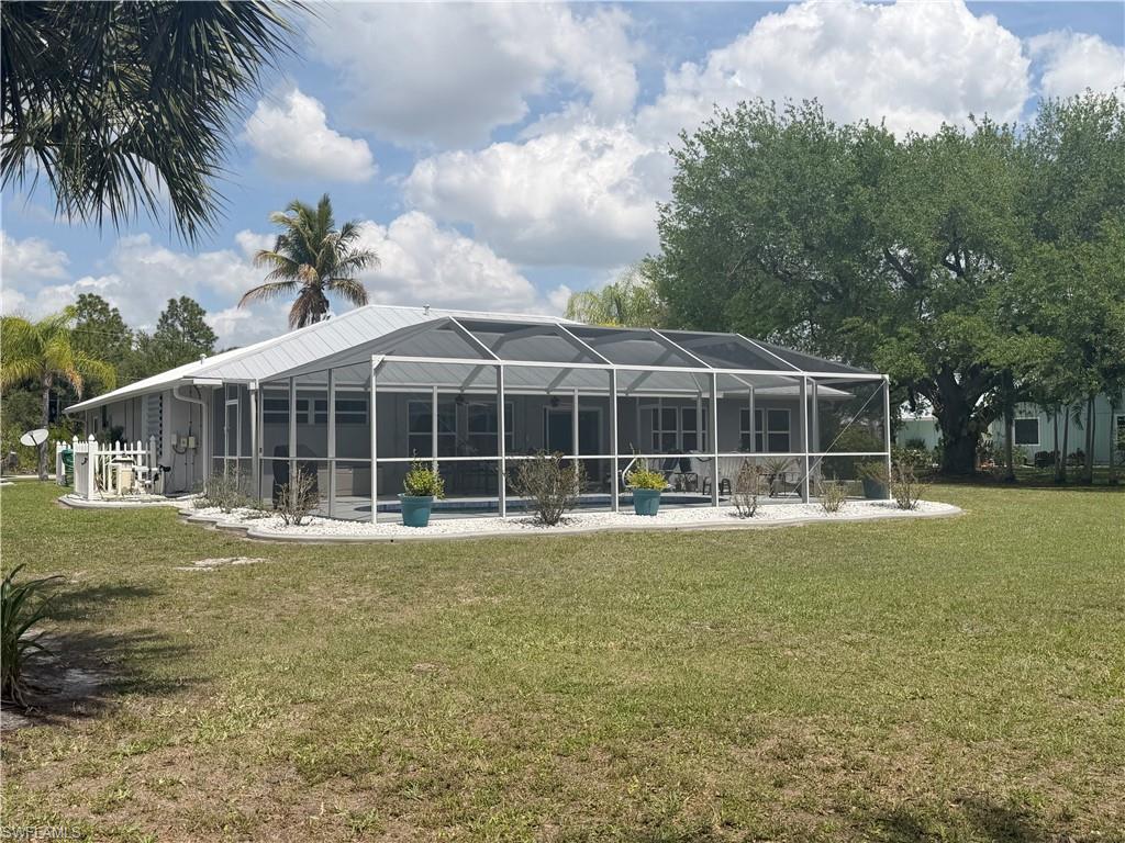 Back of property with glass enclosure, a yard, a sunroom, a pool, and a patio area