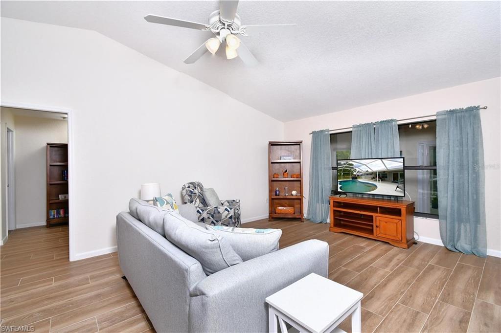 Living area featuring wood tiled floors, vaulted ceiling, and a ceiling fan