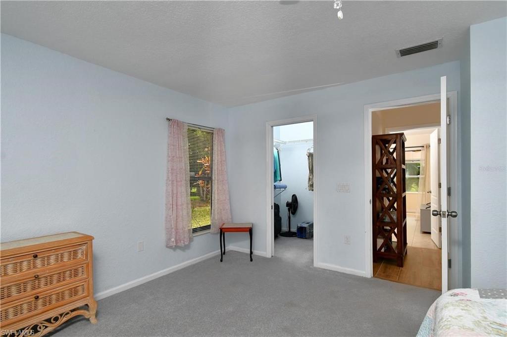 Bedroom featuring a spacious closet, light carpet, and a textured ceiling