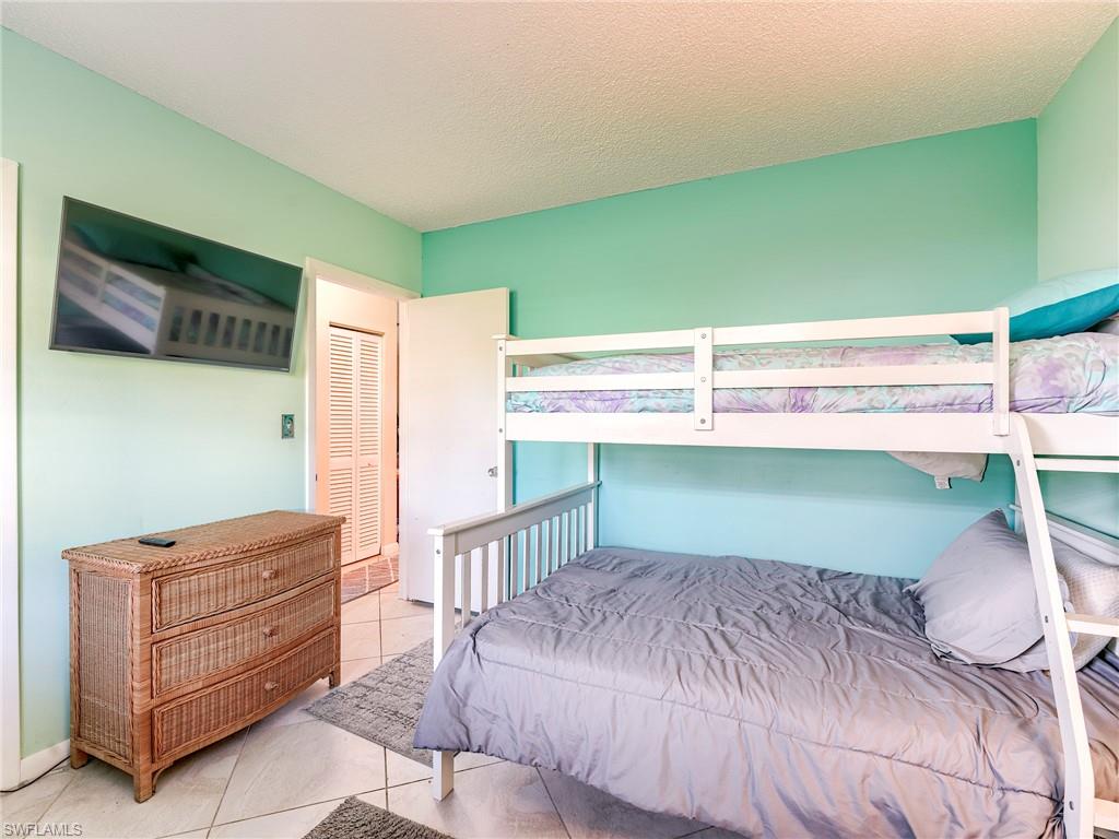 Bedroom with light tile patterned floors, a textured ceiling, and a closet