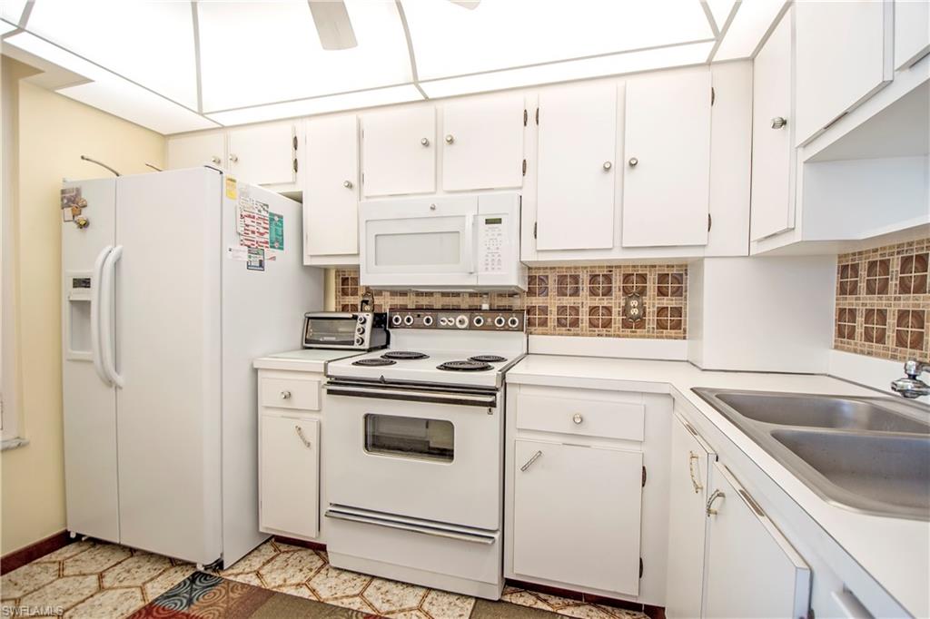 Kitchen featuring white appliances, light countertops, and white cabinetry