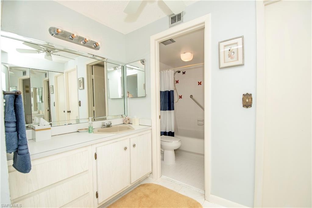 Full bathroom featuring ceiling fan, vanity, shower / bath combination with curtain, and light tile patterned flooring