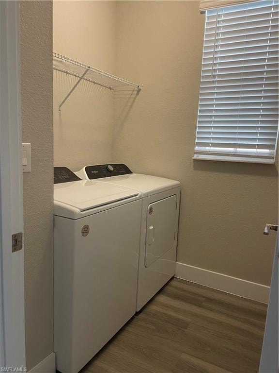 Laundry area featuring dark wood-style floors, separate washer and dryer, and a textured wall
