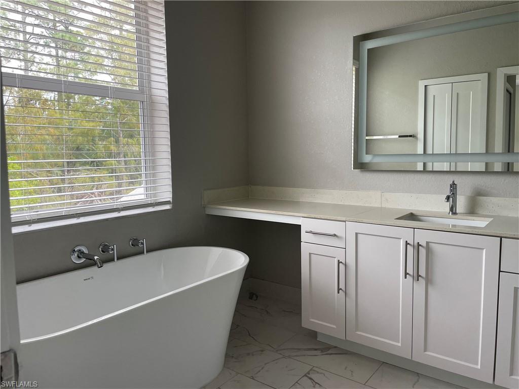 Full bathroom with vanity, a soaking tub, and light marble finish floors