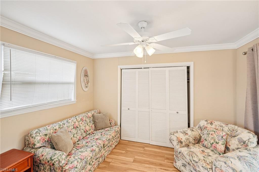 Living area with ornamental molding, light wood-style flooring, and ceiling fan