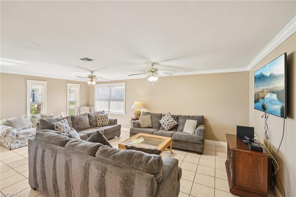 Living room featuring crown molding, light tile patterned floors, and ceiling fan
